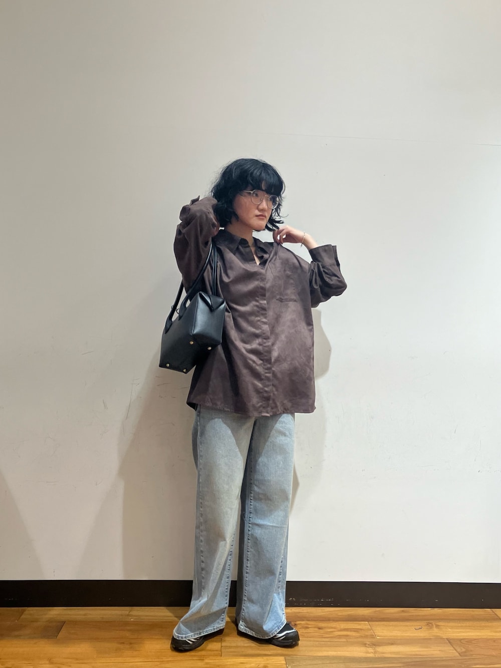 ブルー系のデニムパンツ、ブラウン系のシャツ/ブラウス、ブラック系のショルダーバッグを着用したレディースの秋コーディネートの1枚目の写真