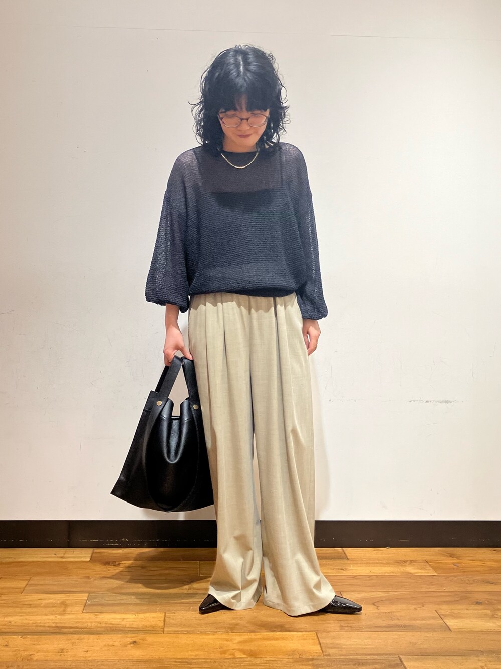 ベージュ系のその他パンツ、グレー系のニット/セーター、ブラック系のトートバッグを着用したレディースの春コーディネートの1枚目の写真