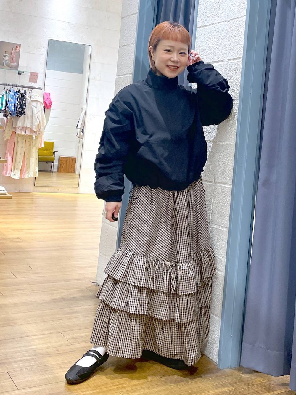 ブラック系のスニーカー、ブラック系のブルゾン、ブラウン系のスカートを着用したレディースの春コーディネートの1枚目の写真