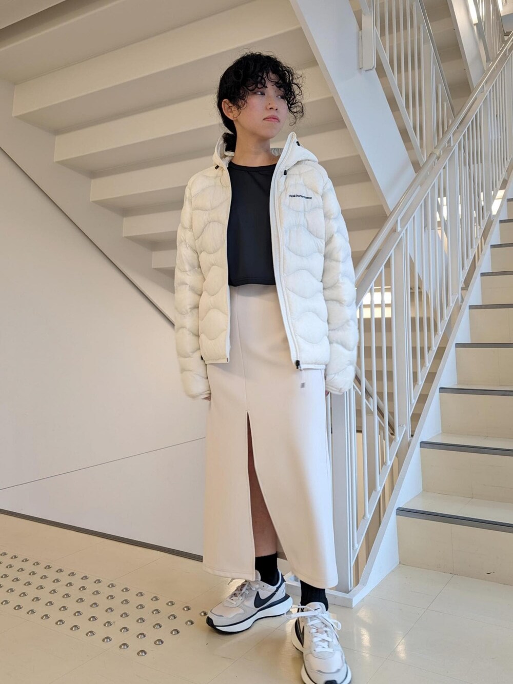 ホワイト系のスカート、ホワイト系のダウンジャケット/コート、ブラック系のTシャツ/カットソーを着用したレディースの冬コーディネートの1枚目の写真