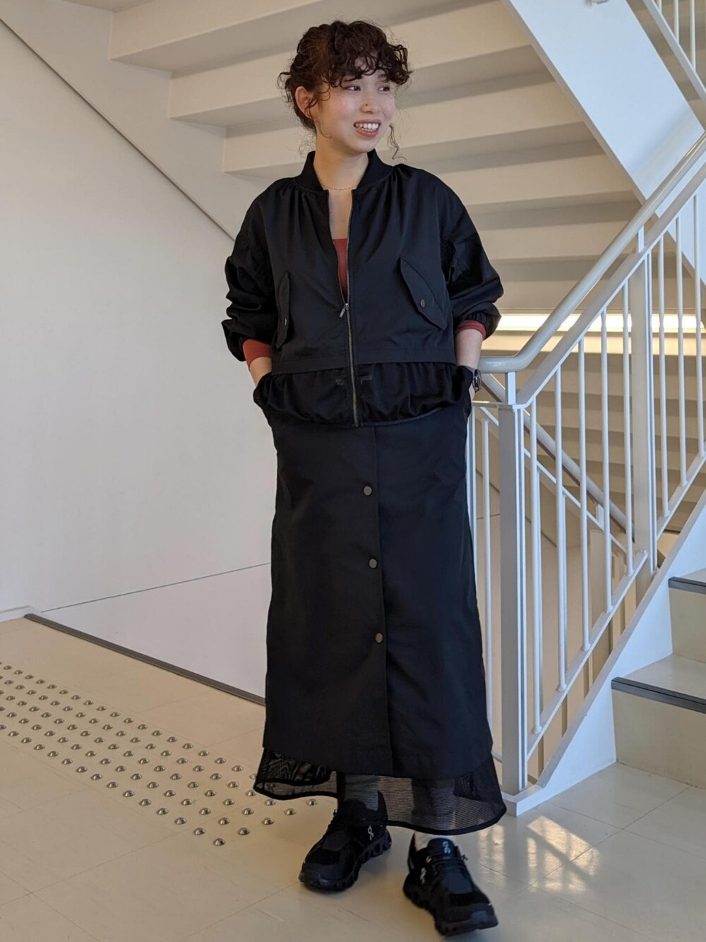 レッド系のTシャツ/カットソー、ブラック系のスニーカー、ブラック系のブルゾンを着用したレディースの春コーディネートの1枚目の写真