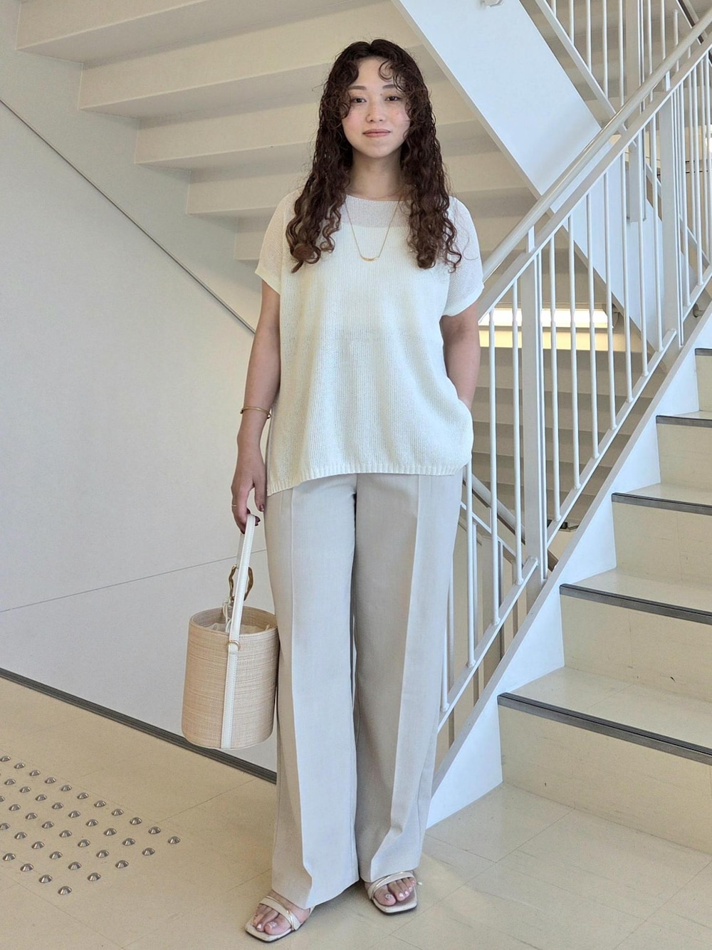 ベージュ系のその他パンツ、ホワイト系のハンドバッグ、ホワイト系のニット/セーターを着用したレディースの夏コーディネートの1枚目の写真