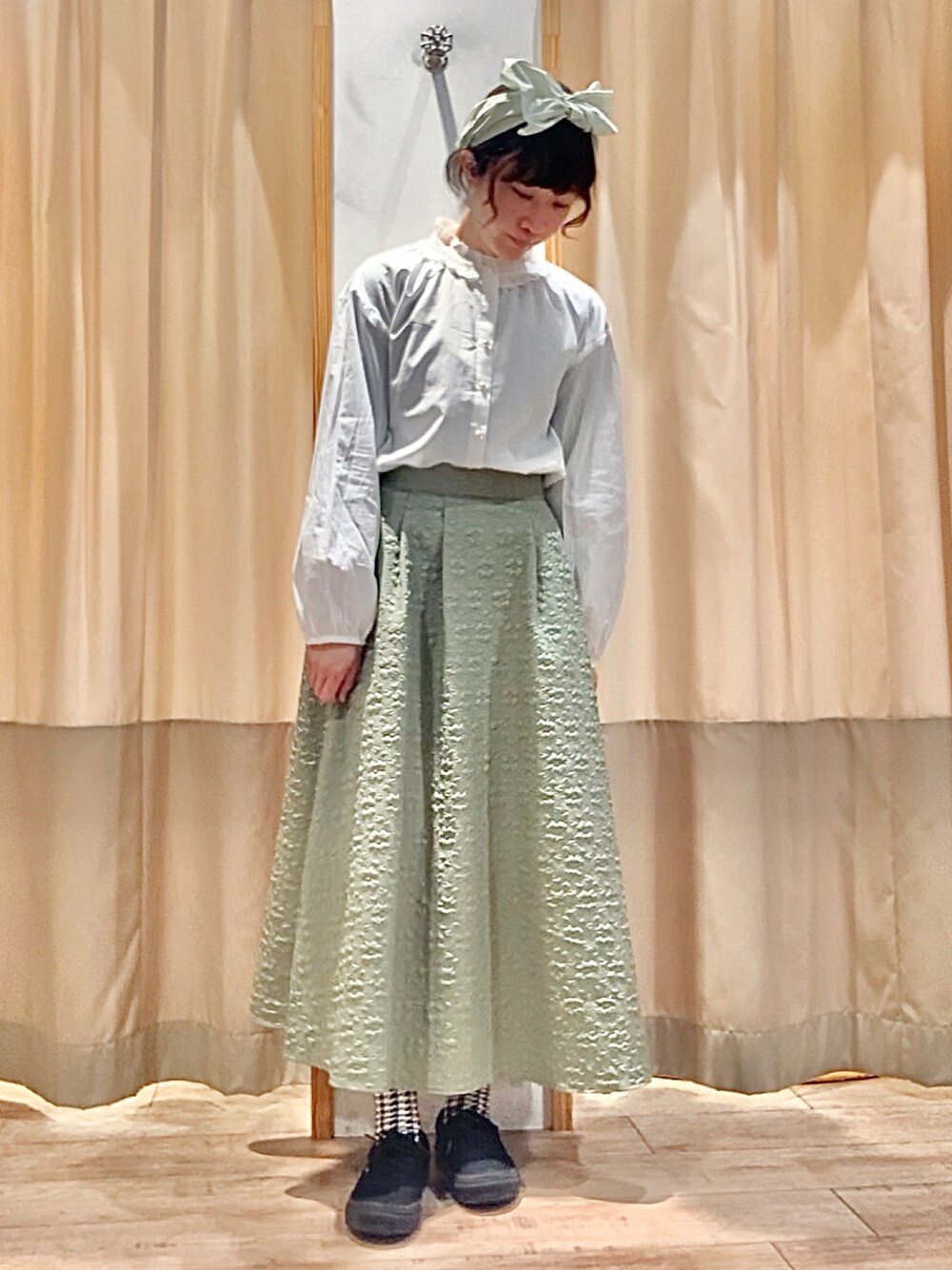 グリーン系のスカート、ホワイト系のシャツ/ブラウス、グリーン系のヘアアクセサリーを着用したレディースの冬コーディネートの1枚目の写真