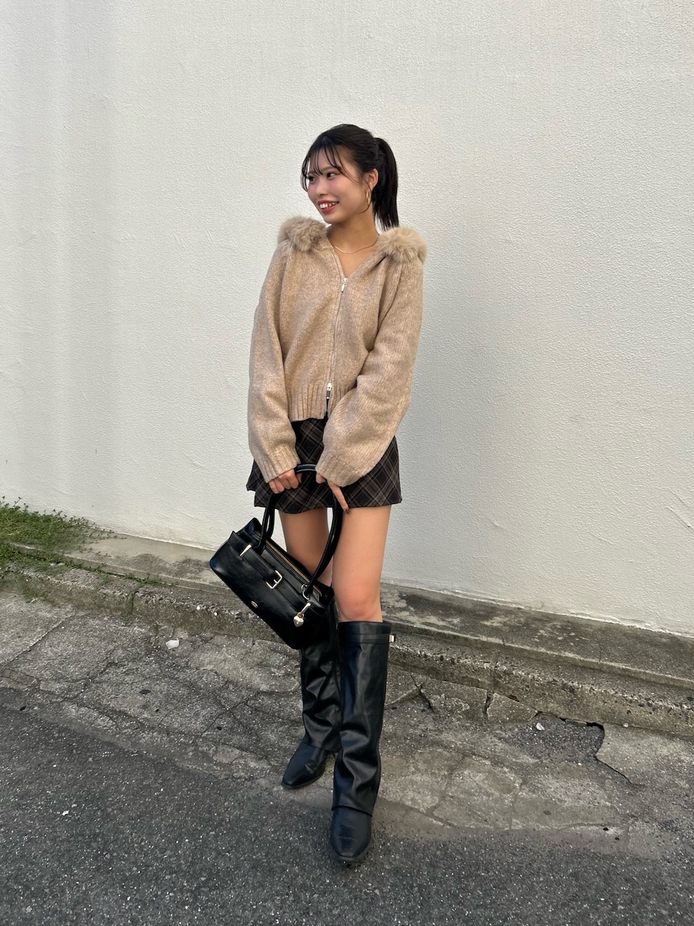 ベージュ系のニット/セーター、グレー系のスカート、ブラック系のボストンバッグを着用したレディースの秋コーディネートの1枚目の写真