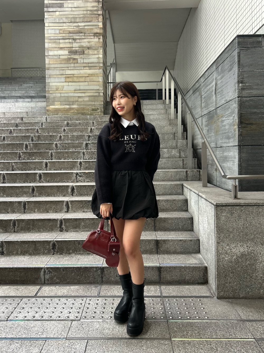 ブラック系のニット/セーター、レッド系のボストンバッグを着用したレディースの夏コーディネートの1枚目の写真