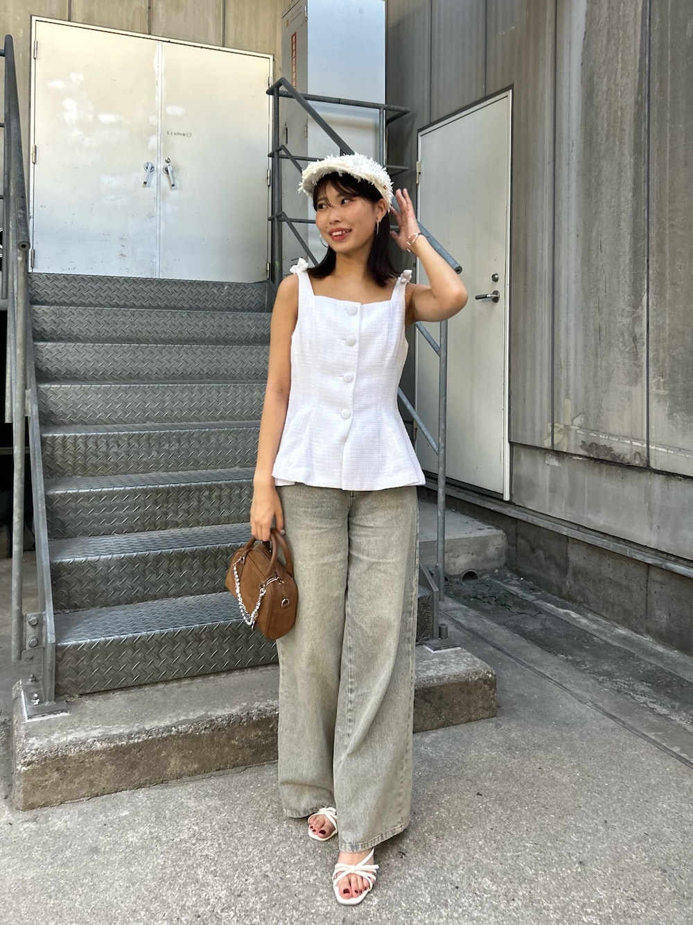ホワイト系のベスト、ブルー系のデニムパンツ、ブラウン系のボストンバッグを着用したレディースの夏コーディネートの1枚目の写真