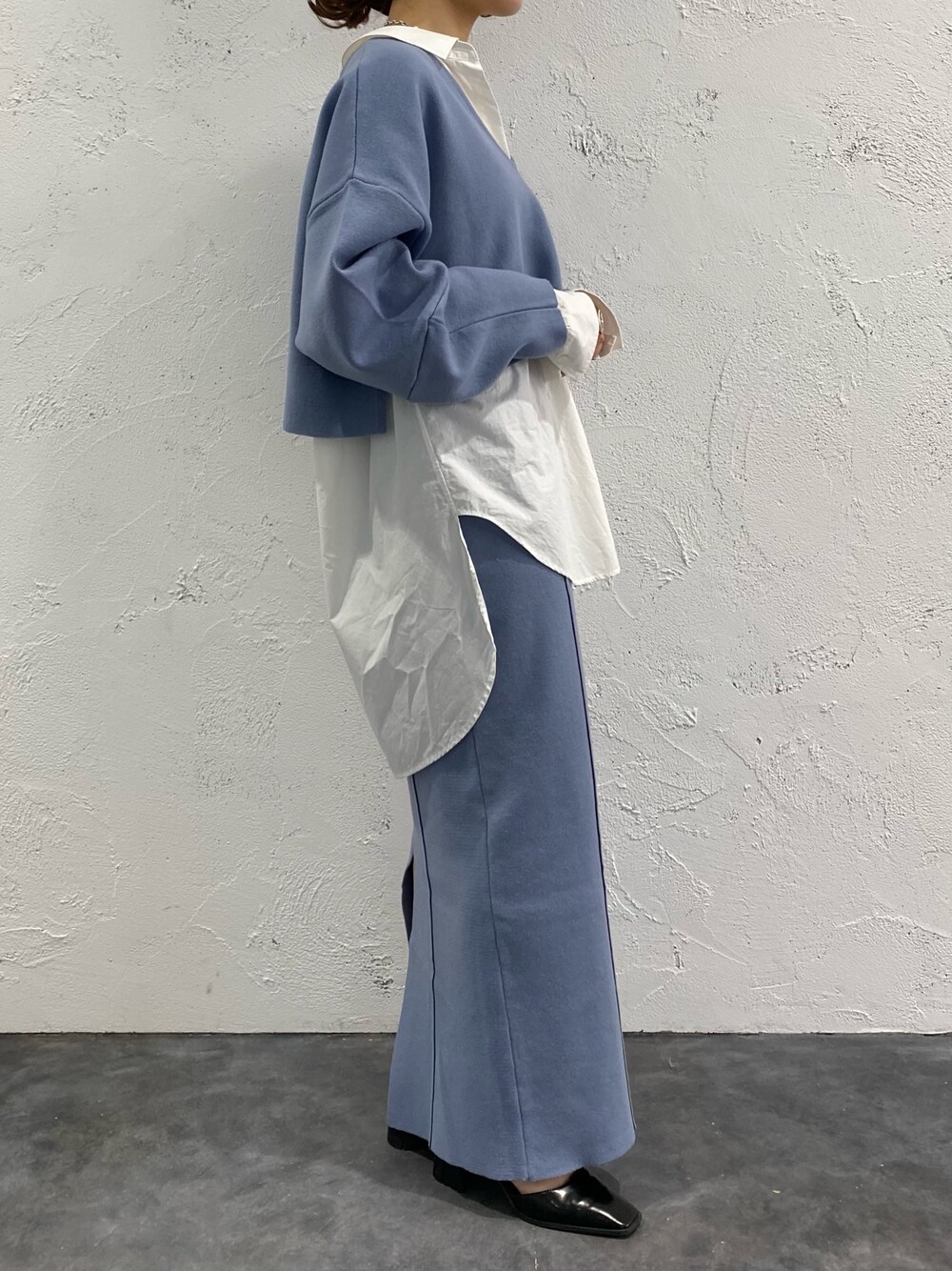 ブルー系のスカート、ブルー系のニット/セーター、ブラック系のパンプスを着用したレディースの冬コーディネートの3枚目の写真