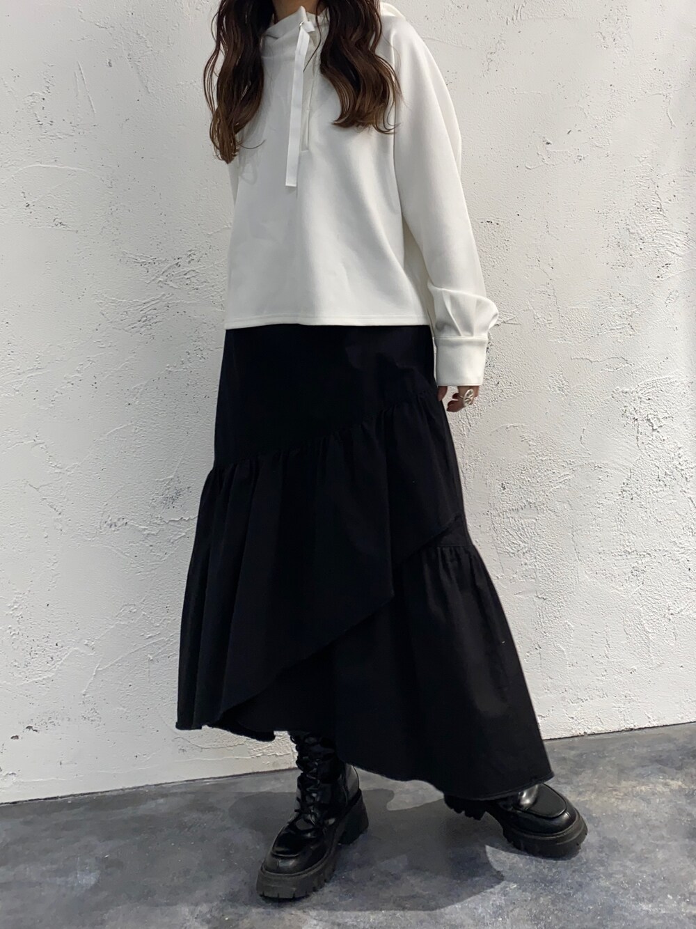 ホワイト系のスカート、ホワイト系のパーカー、ブラック系のブーツを着用したレディースの春コーディネートの3枚目の写真