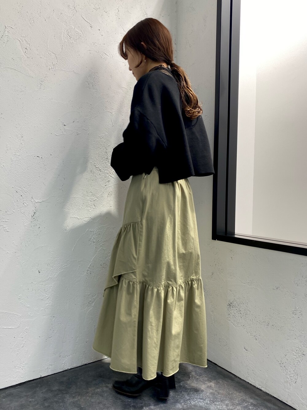 グリーン系のスカート、ブラック系のニット/セーター、ブラック系のTシャツ/カットソーを着用したレディースの冬コーディネートの3枚目の写真