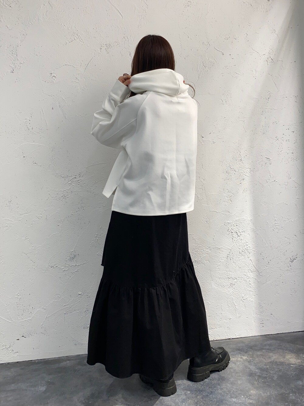 ホワイト系のスカート、ホワイト系のパーカー、ブラック系のブーツを着用したレディースの春コーディネートの2枚目の写真
