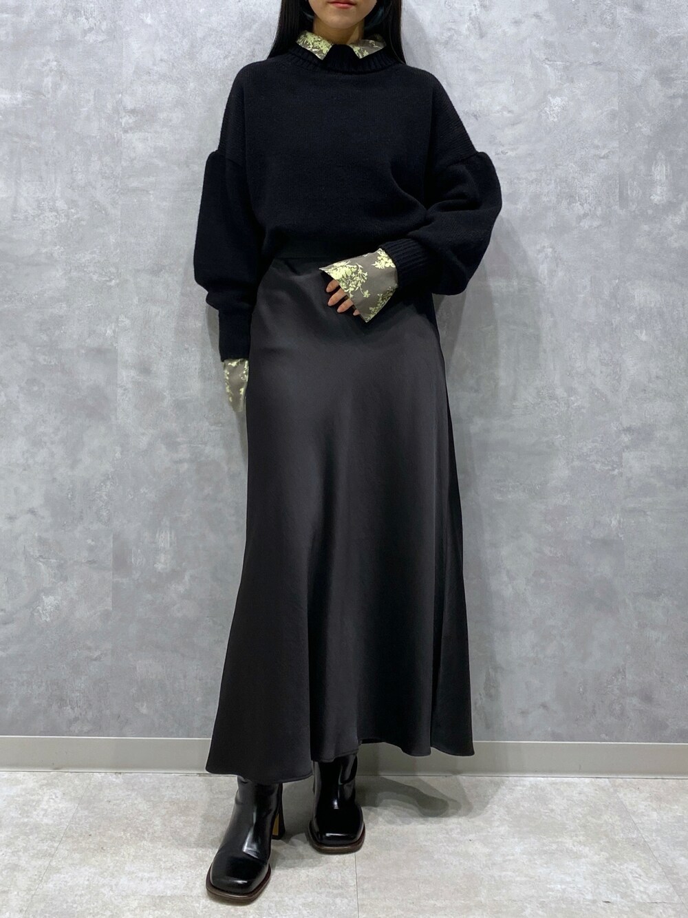 ブラック系のニット/セーター、ブラック系のスカート、グリーン系のシャツ/ブラウスを着用したレディースの秋コーディネートの1枚目の写真