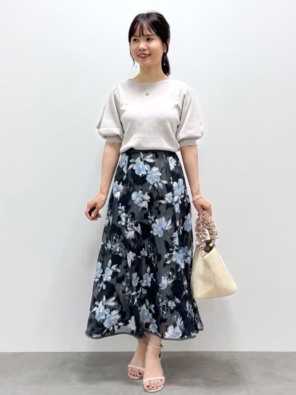 ベージュ系のニット/セーター、グレー系のスカート、ベージュ系のトートバッグを着用したレディースの春コーディネートの1枚目の写真