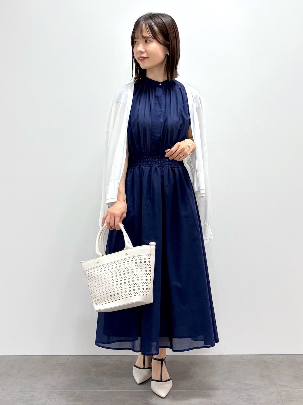 ブルー系のワンピース、ホワイト系のトートバッグ、ベージュ系のパンプスを着用したレディースの春コーディネートの1枚目の写真