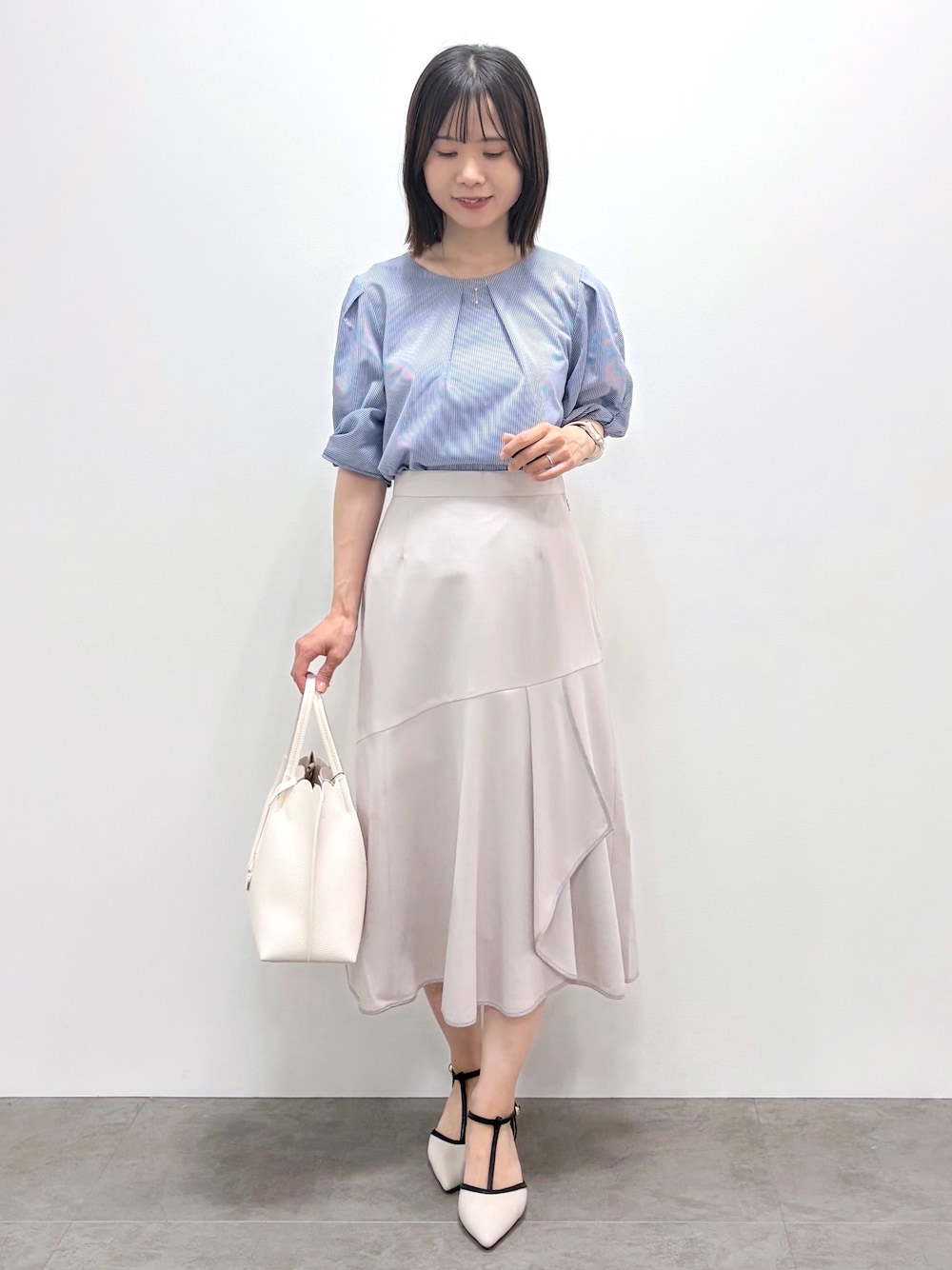 ブルー系のTシャツ/カットソー、ベージュ系のスカート、ホワイト系のトートバッグを着用したレディースの春コーディネートの1枚目の写真