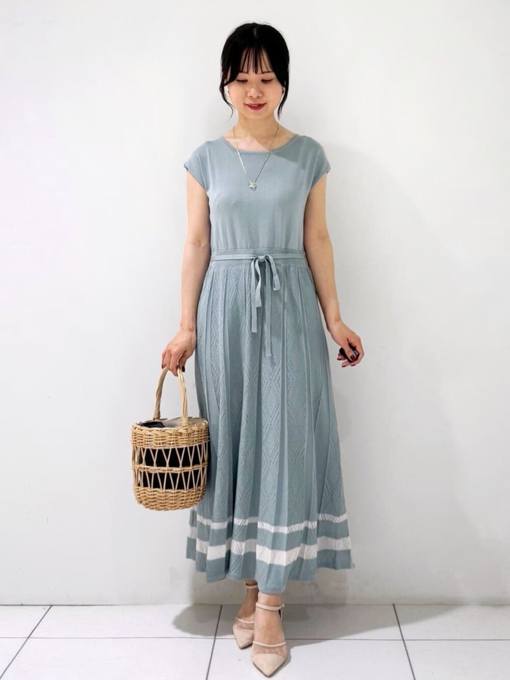 グリーン系のワンピース、ブラック系のハンドバッグ、ベージュ系のパンプスを着用したレディースの夏コーディネートの1枚目の写真