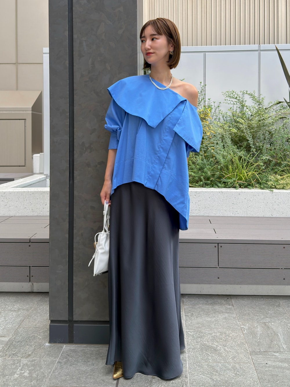 ブルー系のシャツ/ブラウス、グレー系のスカート、ゴールド系のネックレスを着用したレディースの夏コーディネートの1枚目の写真