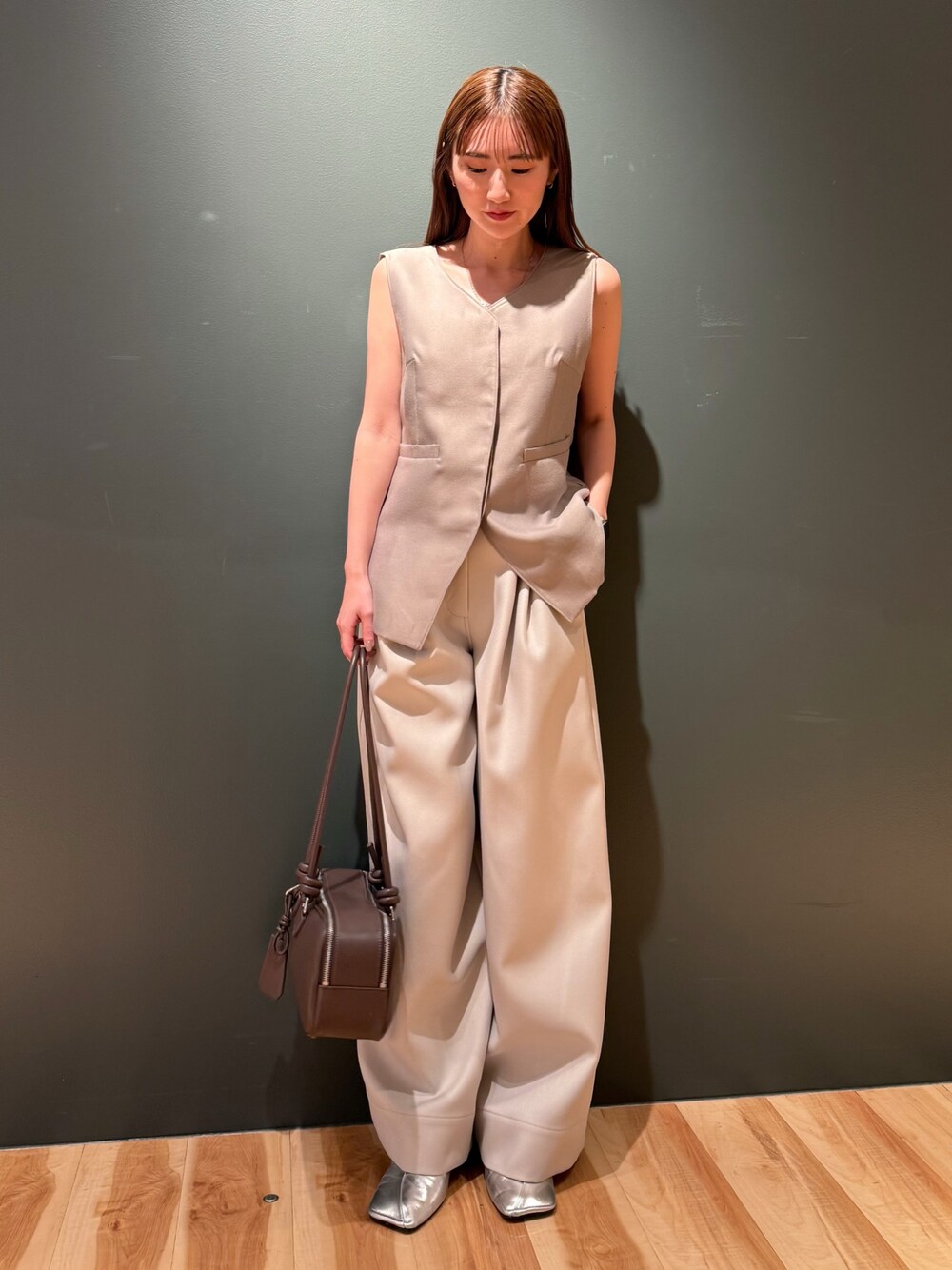 ベージュ系のベスト、ホワイト系のその他パンツ、ブラック系のボストンバッグを着用したレディースの冬コーディネートの1枚目の写真