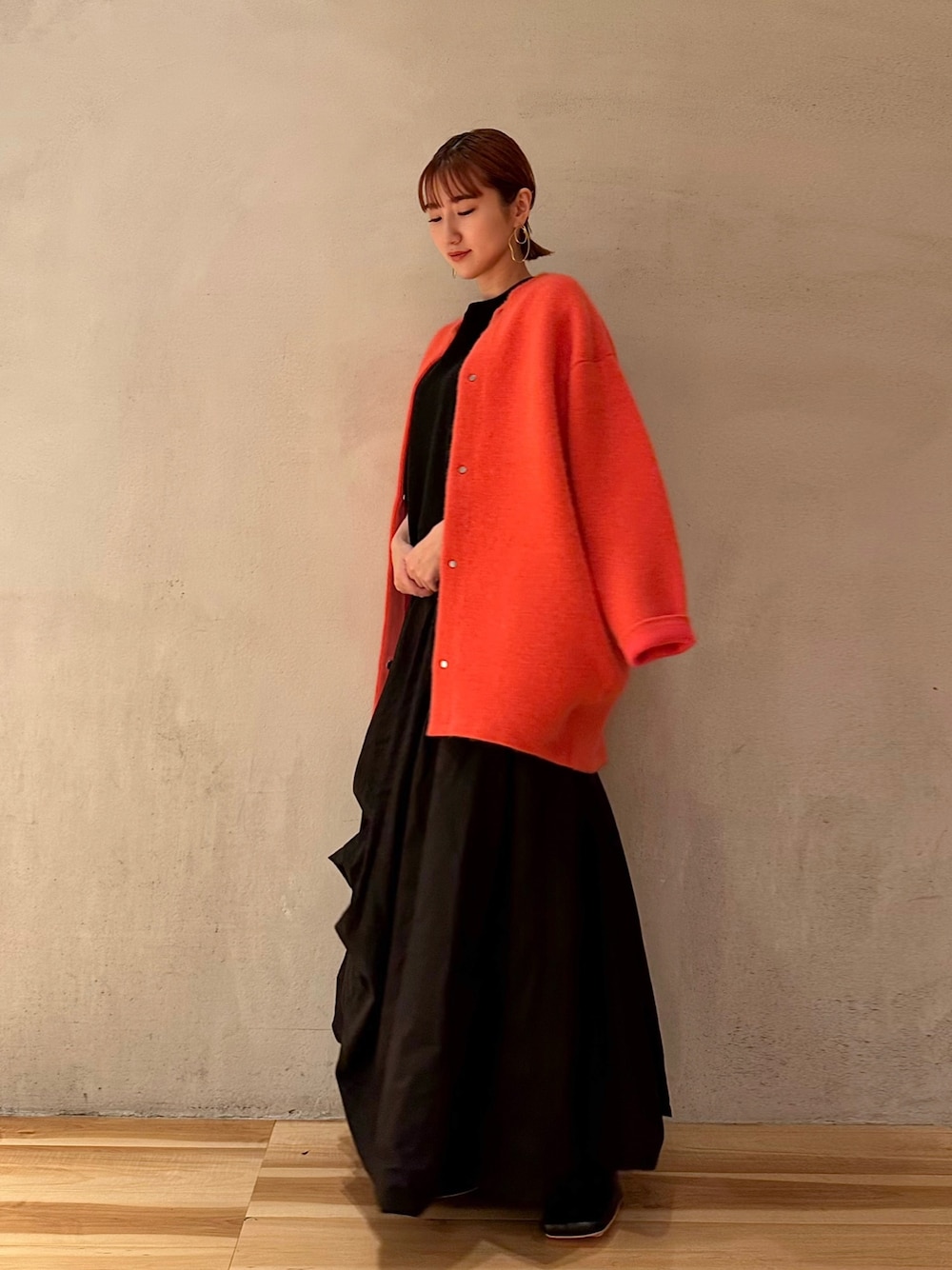 ブラック系のニット/セーター、ブラック系のブーツ、ピンク系のノーカラージャケットを着用したレディースの夏コーディネートの1枚目の写真