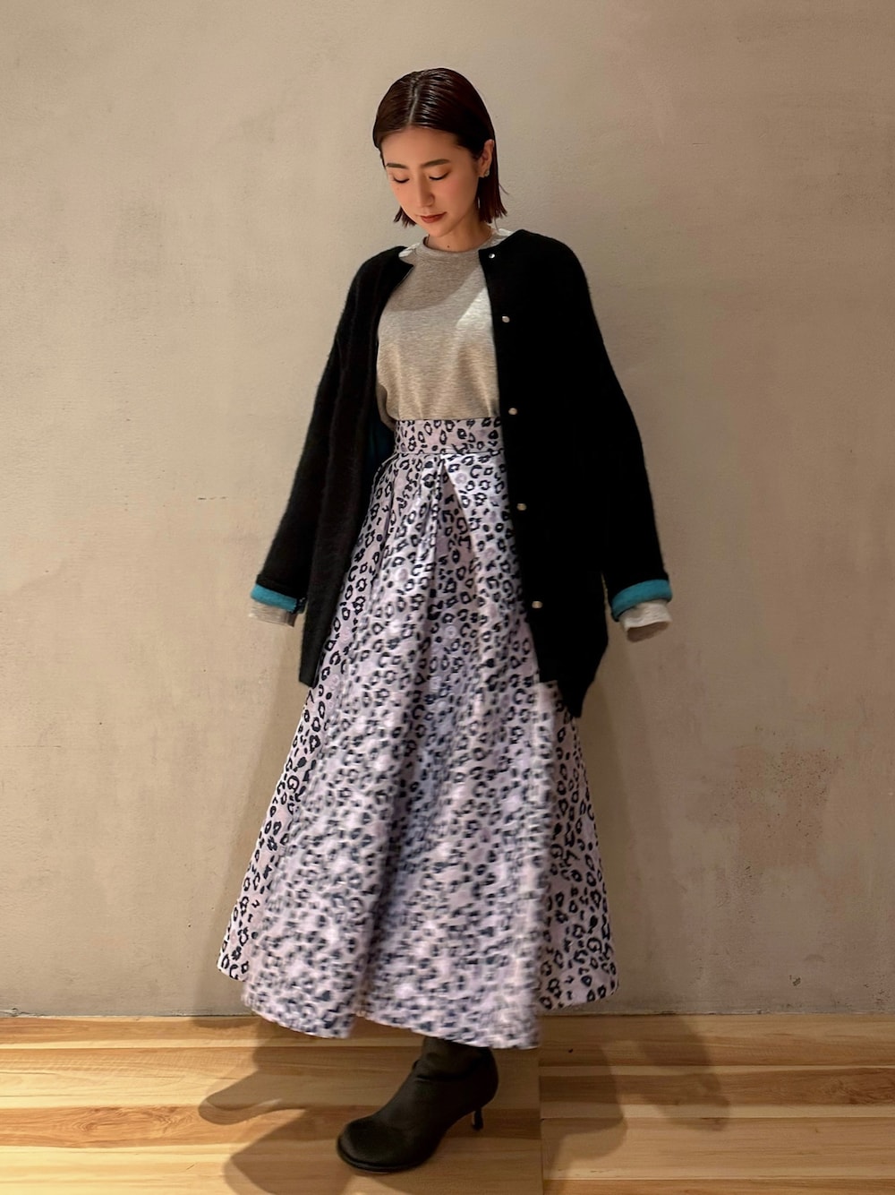 ブラック系のカーディガン/ボレロ、グレー系のTシャツ/カットソー、パープル系のスカートを着用したレディースの冬コーディネートの1枚目の写真