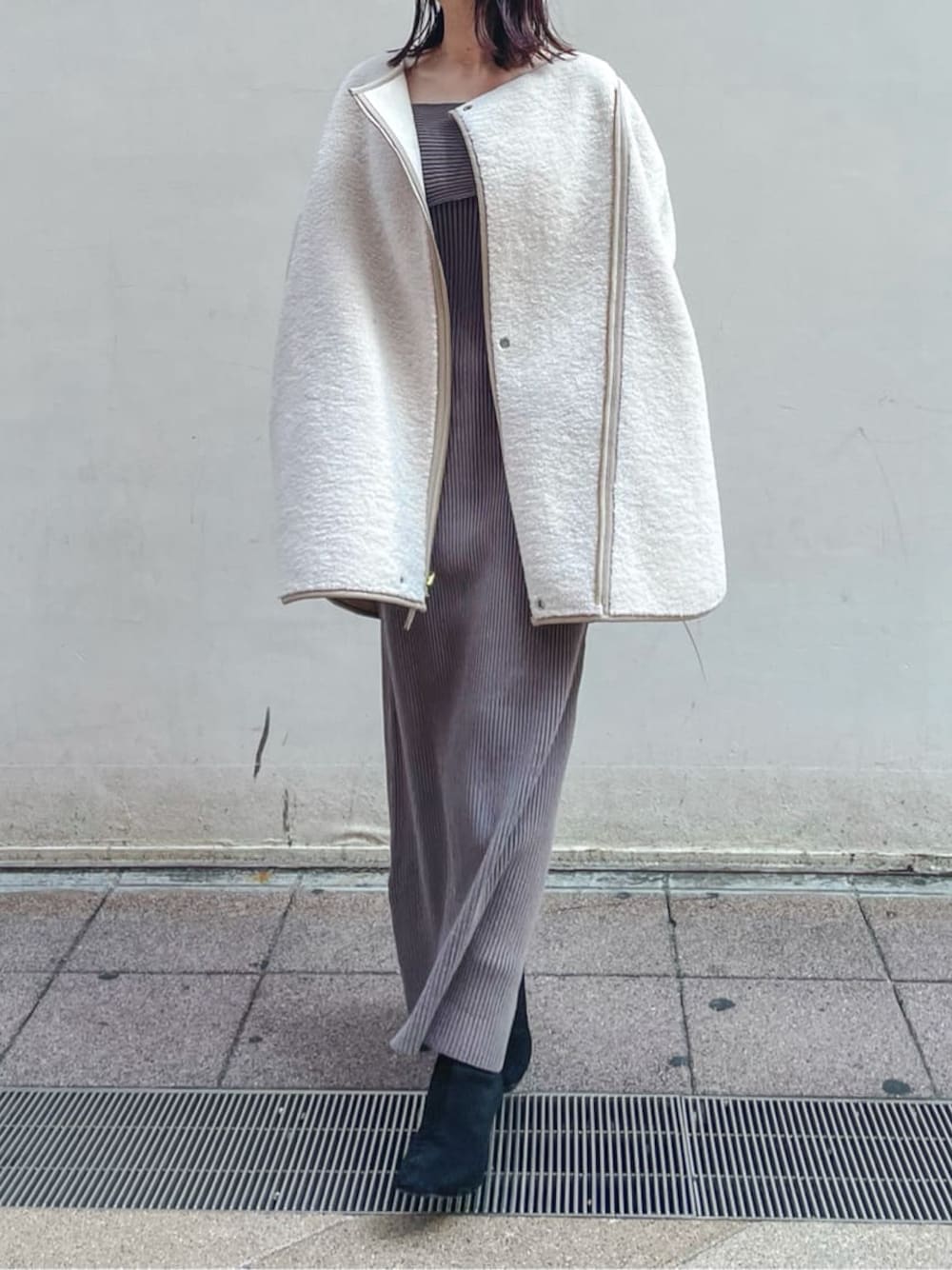 ブラック系のブーツ、ホワイト系のその他アウター、ベージュ系のワンピースを着用したレディースの秋コーディネートの1枚目の写真