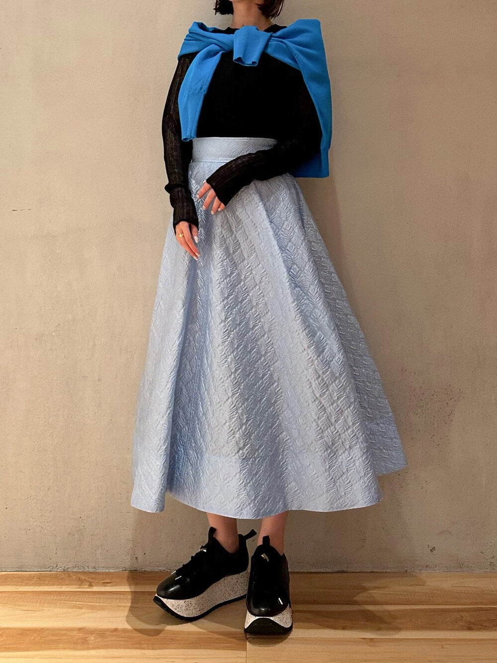 ブルー系のスカート、ブラック系のスニーカー、ブルー系のカーディガン/ボレロを着用したレディースの春コーディネートの1枚目の写真