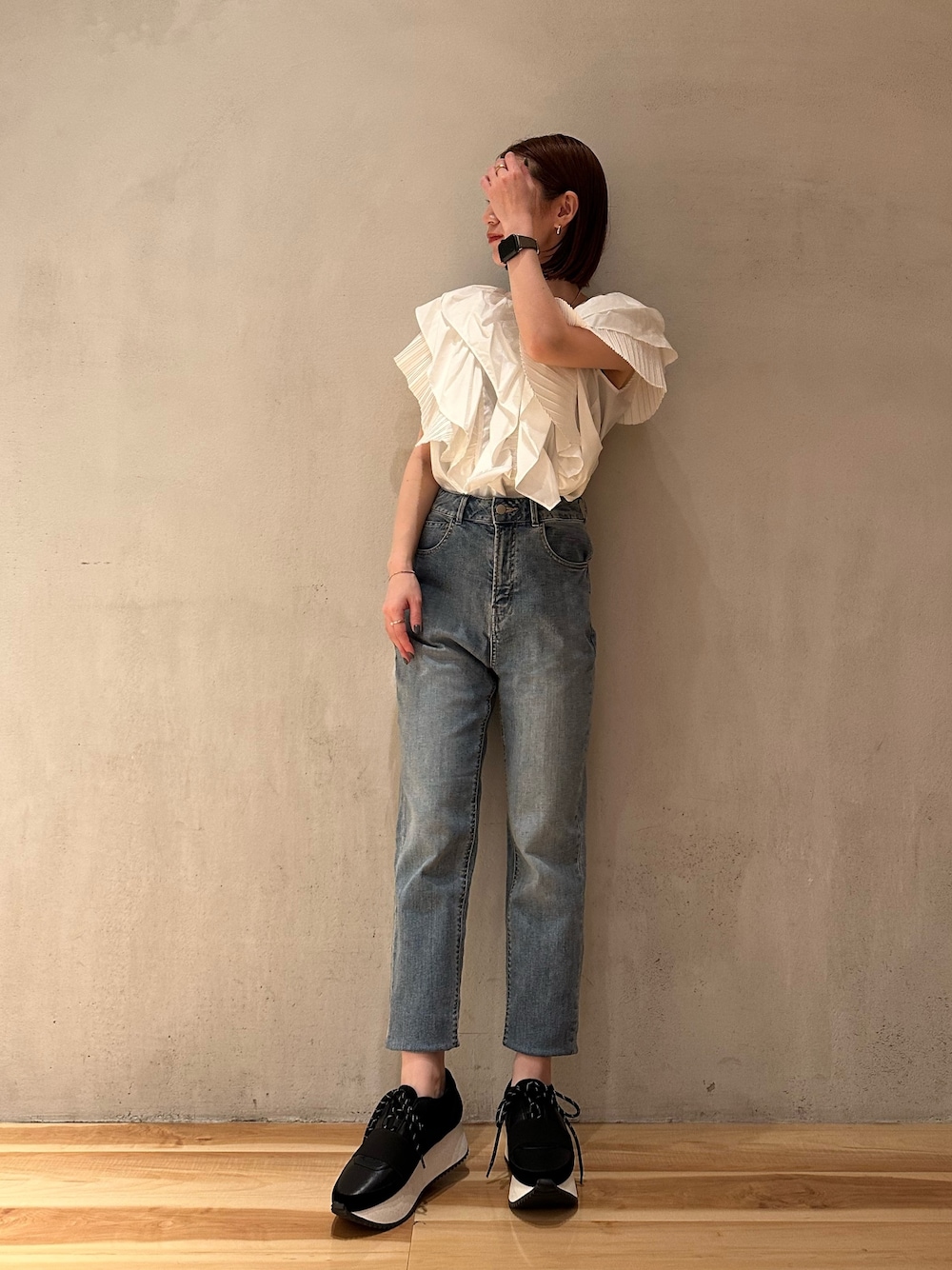 ホワイト系のシャツ/ブラウス、ブラック系のスニーカー、ブルー系のデニムパンツを着用したレディースの春コーディネートの1枚目の写真