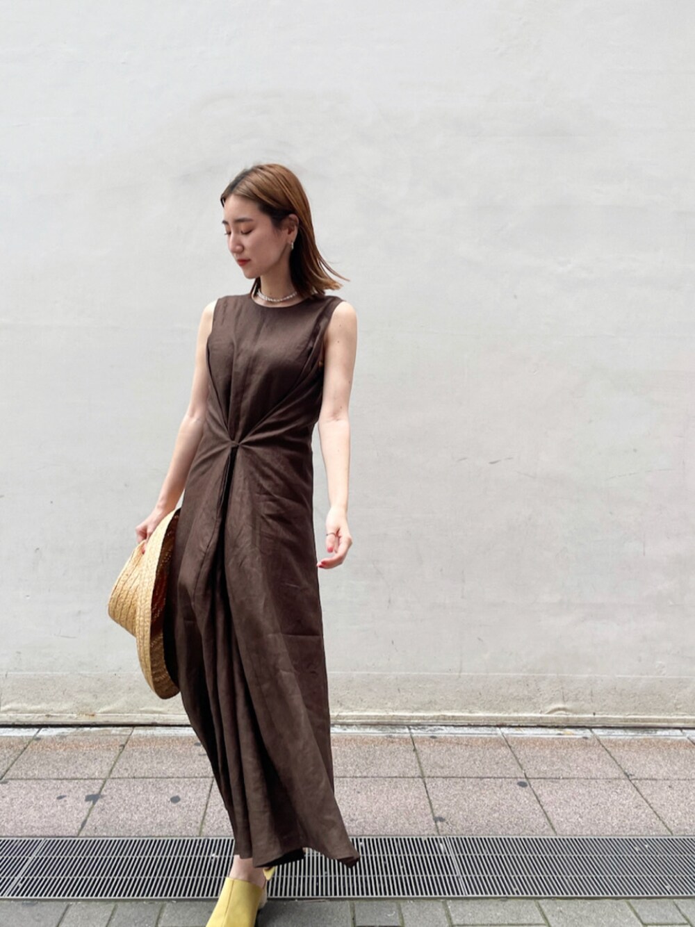 イエロー系のサンダル、ブラウン系のワンピース、ベージュ系のハットを着用したレディースの夏コーディネートの1枚目の写真