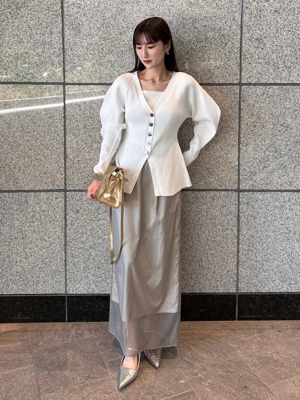 ホワイト系のカーディガン/ボレロ、ベージュ系のスカート、シルバー系のサンダルを着用したレディースの秋コーディネートの1枚目の写真