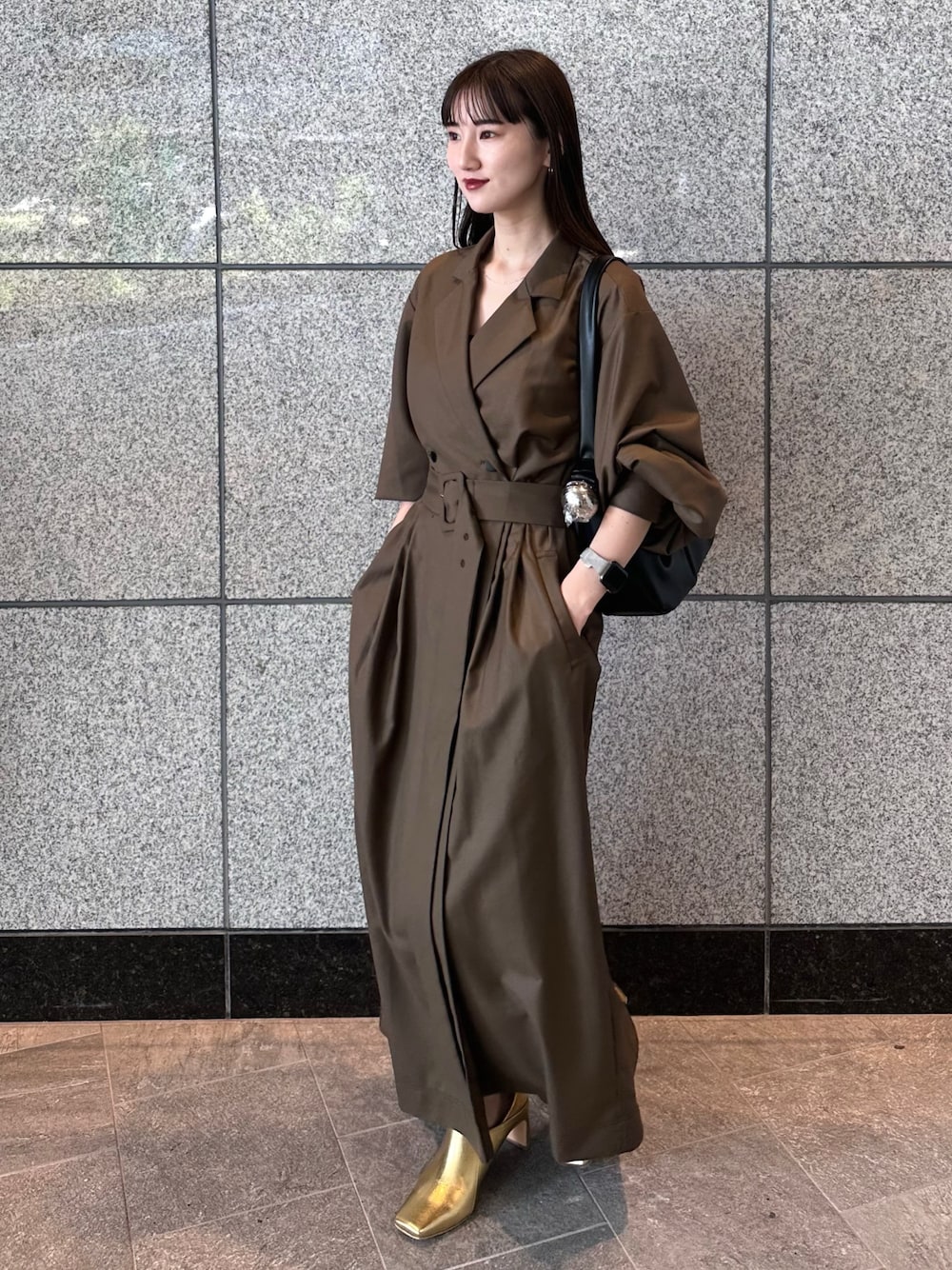 ブラウン系のワンピース、ゴールド系のブーツ、ブラック系のハンドバッグを着用したレディースの秋コーディネートの1枚目の写真