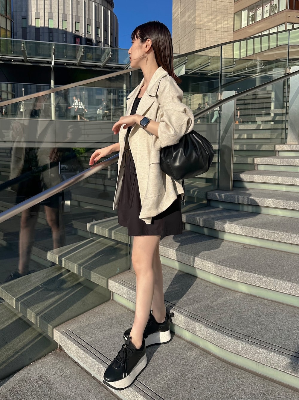 ブラック系のキャミソール、ベージュ系のテーラードジャケット、ブラック系のショルダーバッグを着用したレディースの春コーディネートの1枚目の写真