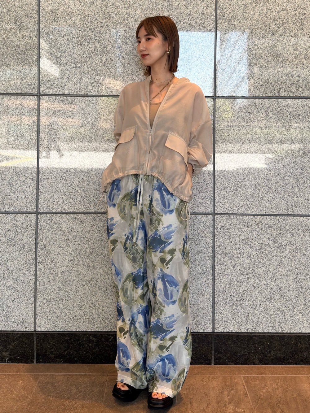 ベージュ系のブルゾン、ブルー系のその他パンツ、ブラウン系のサンダルを着用したレディースの春コーディネートの1枚目の写真