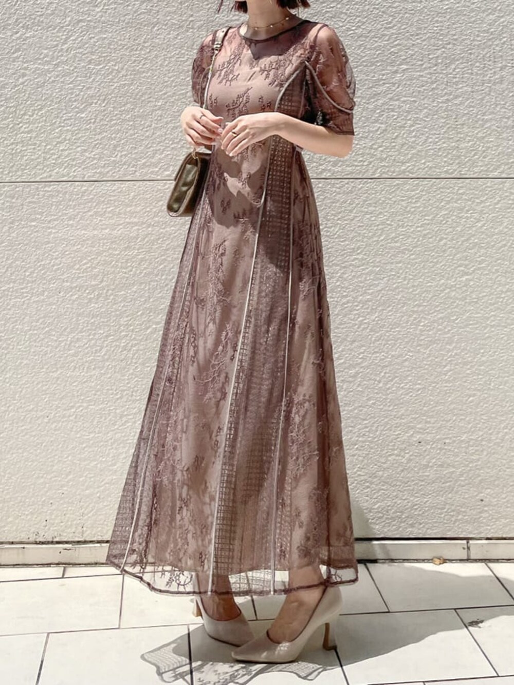 ベージュ系のパンプス、ゴールド系のクラッチバッグ、ベージュ系のドレスを着用したレディースの夏コーディネートの1枚目の写真