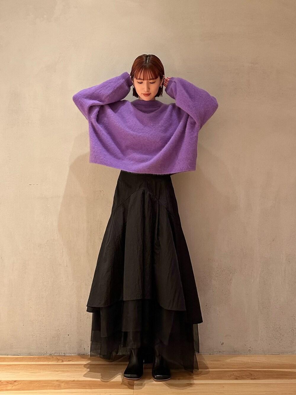 ブラック系のスカート、パープル系のニット/セーター、ブラック系のブーツを着用したレディースの秋コーディネートの1枚目の写真