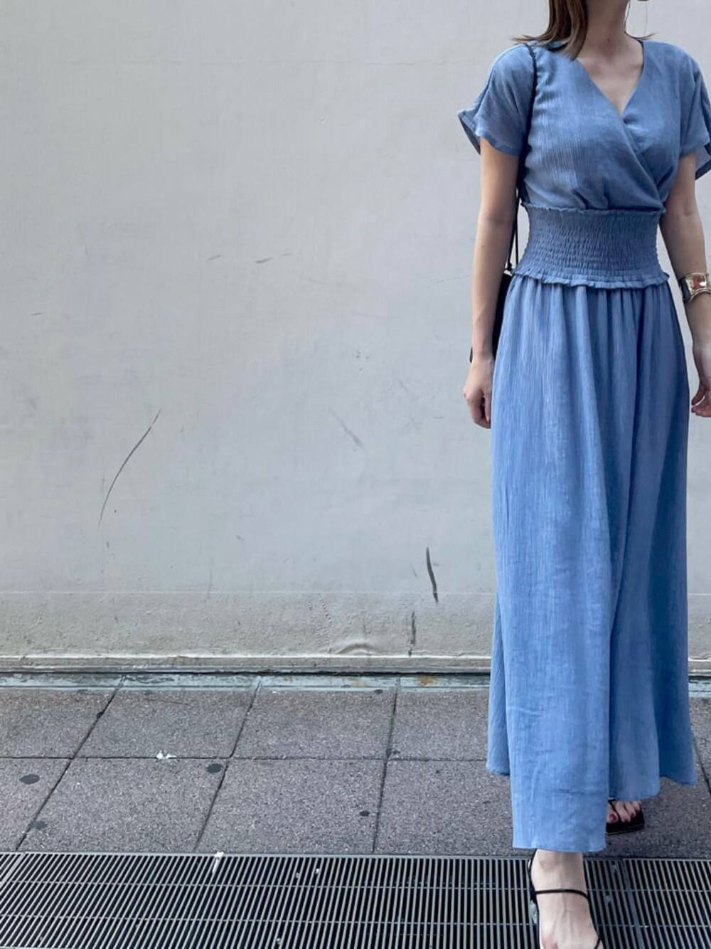 ブラック系のハンドバッグ、ブラック系のサンダル、ブルー系のワンピースを着用したレディースの夏コーディネートの1枚目の写真