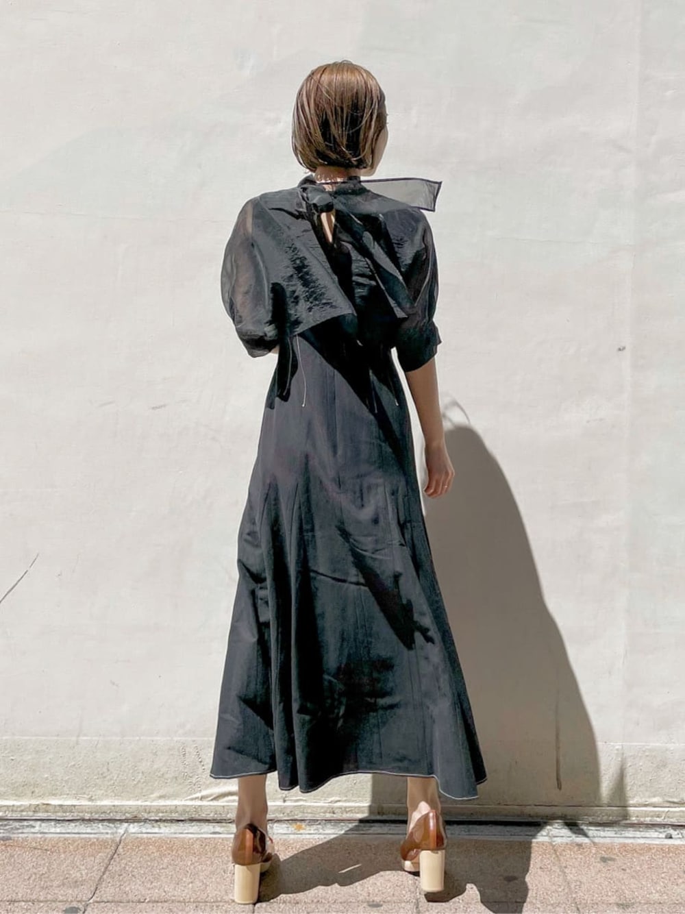 ブラウン系のパンプス、ブラック系のワンピース、ゴールド系のブレスレットを着用したレディースの春コーディネートの1枚目の写真