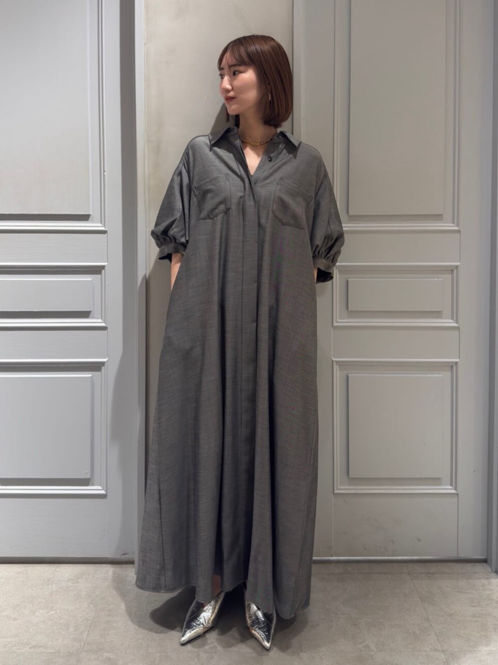 ブラック系のパンプス、グレー系のワンピースを着用したレディースの春コーディネートの1枚目の写真