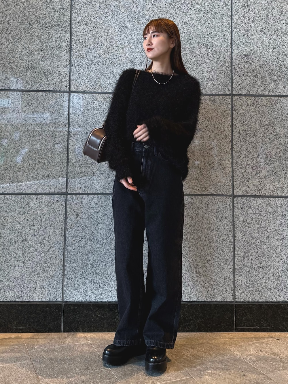 ブラック系のニット/セーター、ブラック系のデニムパンツ、ブラウン系のボストンバッグを着用したレディースの冬コーディネートの1枚目の写真