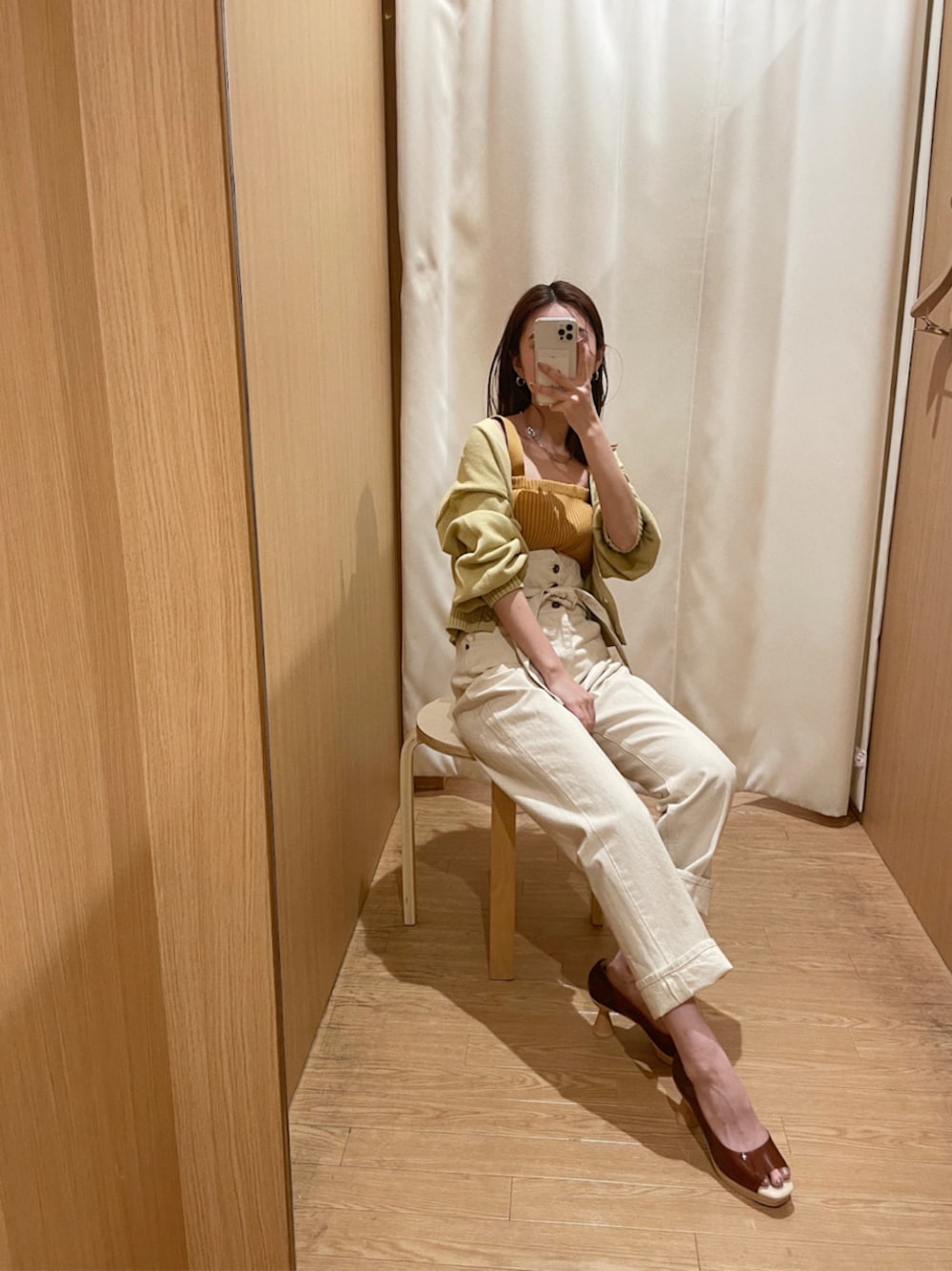 ホワイト系のデニムパンツ、ブラウン系のパンプス、パープル系のハンドバッグを着用したレディースの冬コーディネートの1枚目の写真