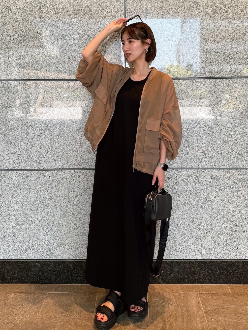 ベージュ系のブルゾン、ブラック系のワンピース、ブラック系のサングラスを着用したレディースの夏コーディネートの1枚目の写真