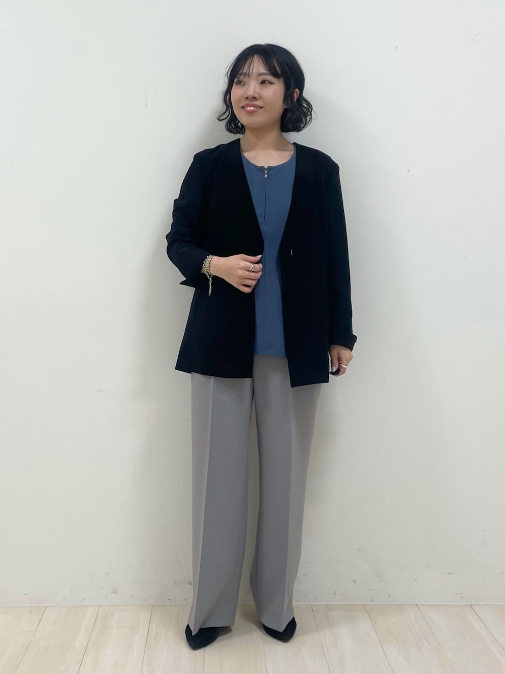 グレー系のスーツパンツ、ブルー系のシャツ/ブラウス、ブラック系のノーカラージャケットを着用したレディースの春コーディネートの1枚目の写真