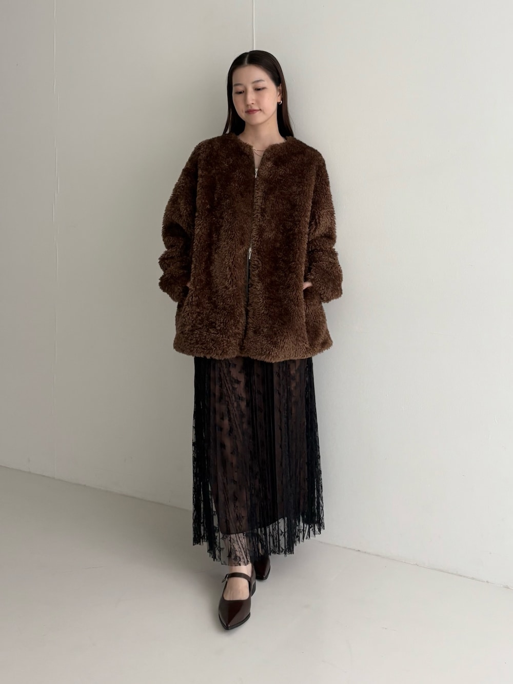 ブラウン系のノーカラージャケット、ブラック系のスカートを着用したレディースの秋コーディネートの1枚目の写真