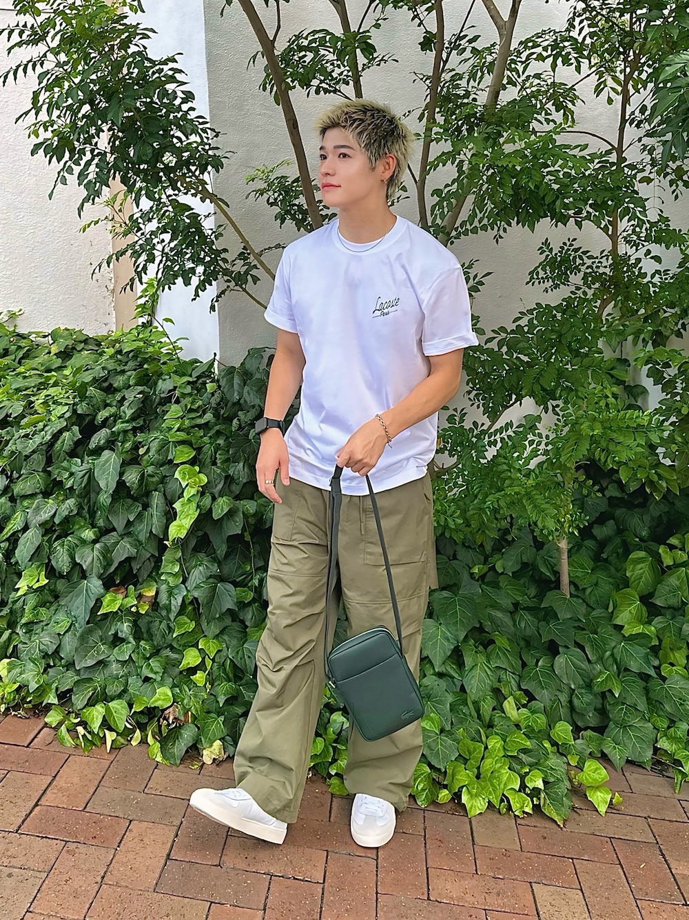 ホワイト系のTシャツ/カットソー、グリーン系のショルダーバッグ、ホワイト系のスニーカーを着用したメンズの秋コーディネートの1枚目の写真