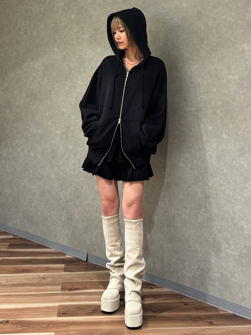 ホワイト系のブーツ、ブラック系のスカート、ブラック系のパーカーを着用したレディースの秋コーディネートの1枚目の写真