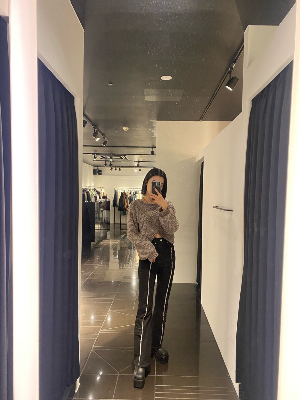 グレー系のニット/セーター、ブラック系のデニムパンツ、ブラック系のブーツを着用したレディースの秋コーディネートの1枚目の写真