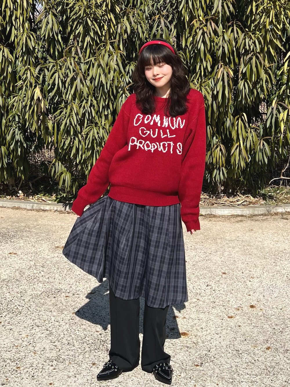 レッド系のニット/セーター、ブラック系のスカート、ブラック系のスラックスを着用したレディースの春コーディネートの1枚目の写真