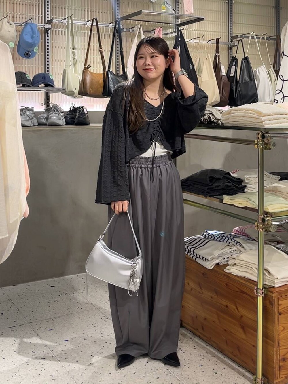 シルバー系のトートバッグ、シルバー系のパンプス、ブラック系のニット/セーターを着用したレディースの春コーディネートの1枚目の写真