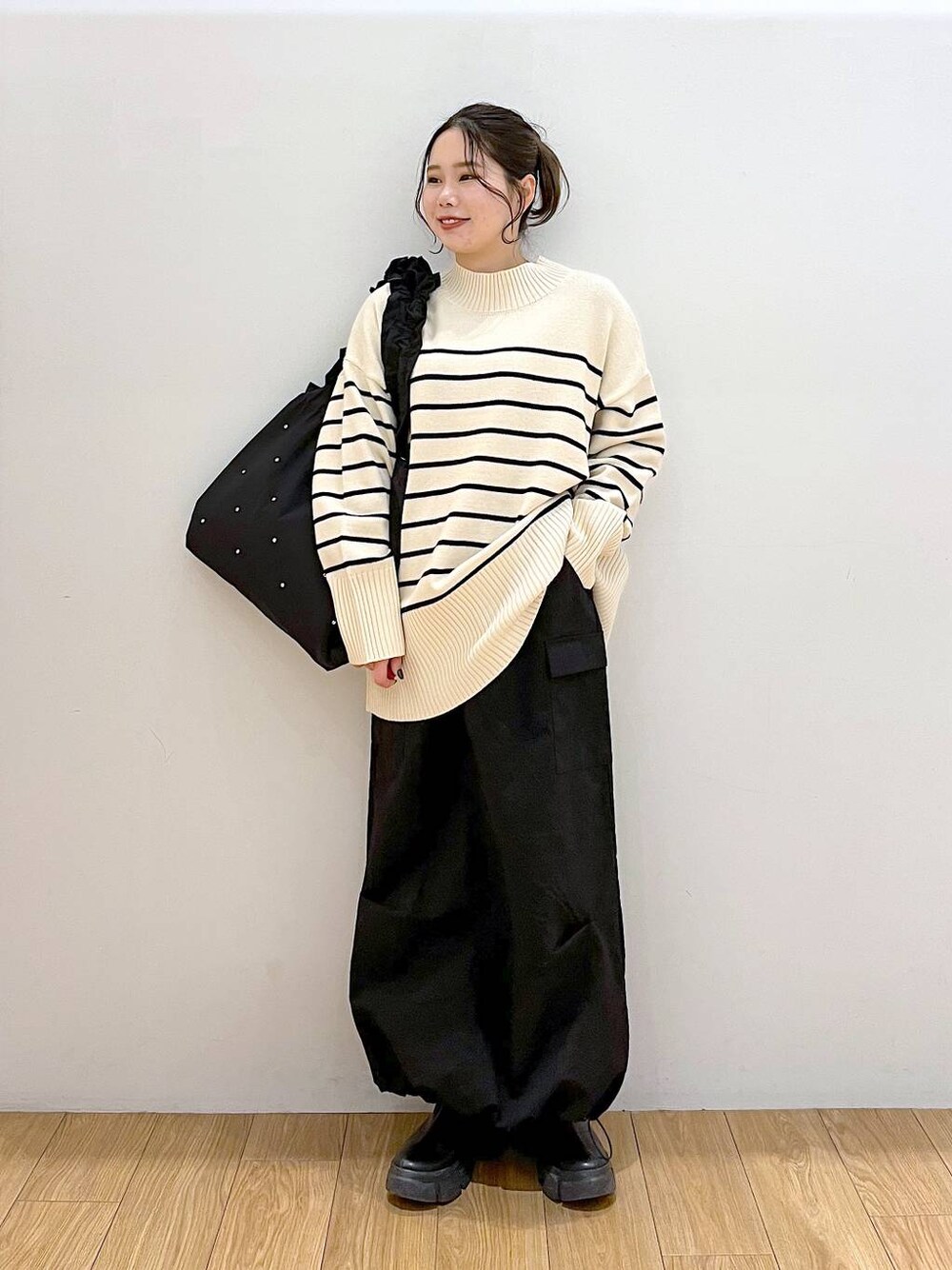 ブラック系のブーツ、その他のニット/セーター、ブラック系のトートバッグを着用したレディースの冬コーディネートの1枚目の写真