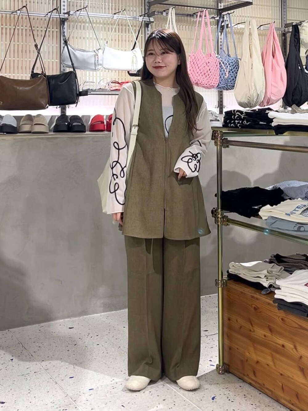 ブラウン系のスラックス、ブラウン系のベスト、ホワイト系のスニーカーを着用したレディースの春コーディネートの1枚目の写真