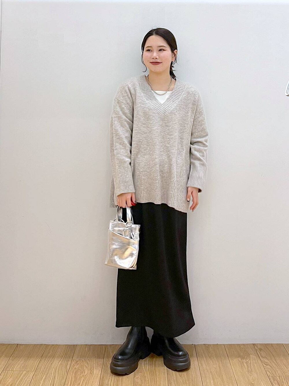 ホワイト系のTシャツ/カットソー、グレー系のニット/セーター、ブラック系のブーツを着用したレディースの冬コーディネートの1枚目の写真
