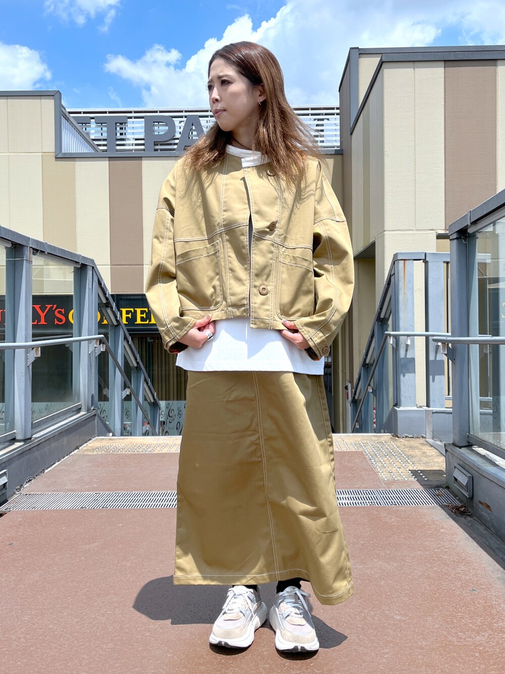 ブラウン系のスカート、ブラウン系のブルゾン、ホワイト系のTシャツ/カットソーを着用したレディースの夏コーディネートの1枚目の写真